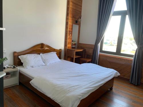 a bedroom with a large bed and a large window at HUNA House in Da Lat