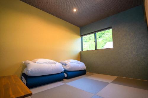 a room with two beds in a room with a window at LOCOMOTION COFFEE AND BED in Tateyama