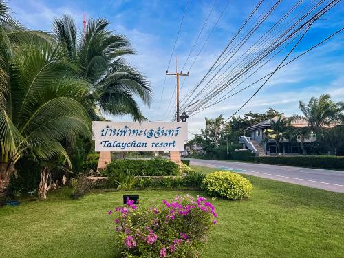 a sign for a restaurant on a street with flowers at Baan Faa Talaychan Resort in Chao Lao Beach