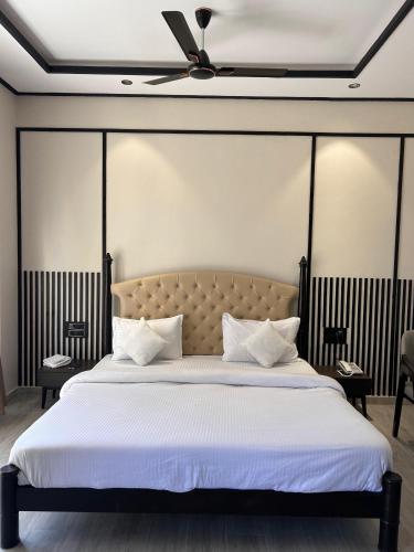 a bedroom with a large bed with white sheets and a ceiling at THE PREMIER GIR RESORT in Sasan Gir