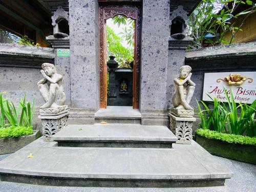 two statues of people standing in front of a building at Aura Bisma Guesthouse in Ubud