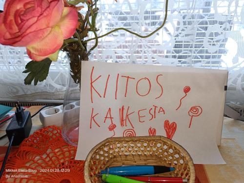 a sign on a table with a vase with a flower at Ristiina Apartment with Sauna in Ristiina