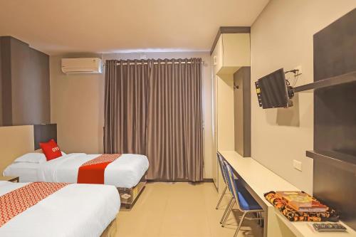 a hotel room with two beds and a television at Super OYO Capital O 92096 Kuala Ulee Lheue Residence Syariah in Banda Aceh