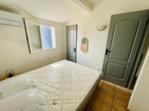 uma cama branca num quarto com uma porta em Maison au bord de l'eau em Gruissan