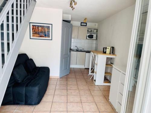 uma sala de estar com um sofá preto e uma cozinha em Maison au bord de l'eau em Gruissan