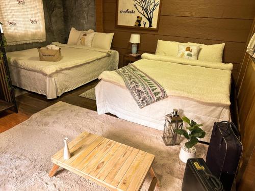 a room with two beds and a table in it at บ้านพักกึ๊ดเติง แม่กำปอง เชียงใหม่ in Mae On