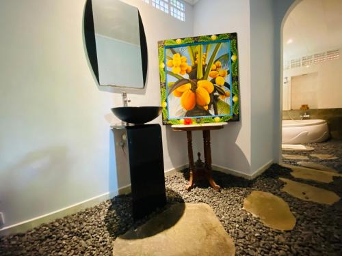 a painting on a wall next to a mirror at Aura Bisma Guesthouse in Ubud