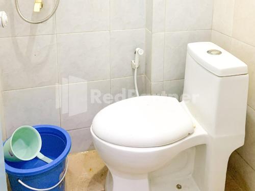 a bathroom with a white toilet and a trash can at RedDoorz Syariah @ D'KostMarto UTY in Yogyakarta
