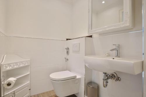 a white bathroom with a sink and a toilet at Haus Miramar Treffert Appartement 21 in Niendorf