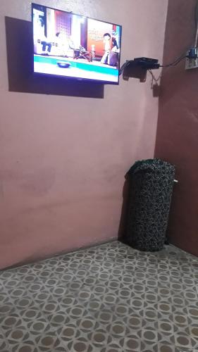 - une télévision à écran plat sur un mur avec une poubelle dans l'établissement Vinayak Niwas, à Miraj
