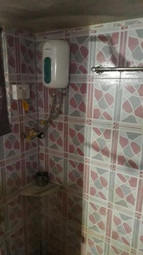 La salle de bains est pourvue d'une douche avec du carrelage rose et blanc. dans l'établissement Vinayak Niwas, à Miraj
