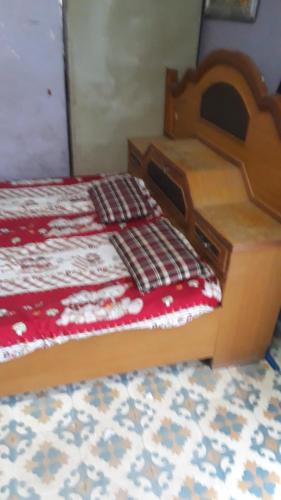- un lit en bois avec une couverture rouge et blanche dans l'établissement Vinayak Niwas, à Miraj