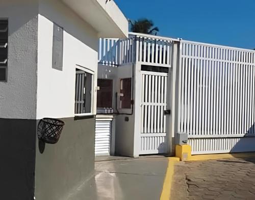 um edifício branco com um portão e uma cerca em Apartamento Belas Artes Itanhaém em Itanhaém