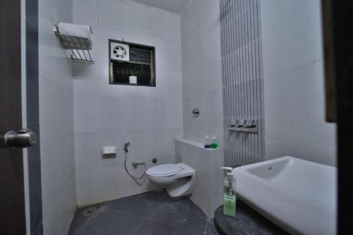 a white bathroom with a toilet and a bath tub at Hotel Saishree` in Shirdi