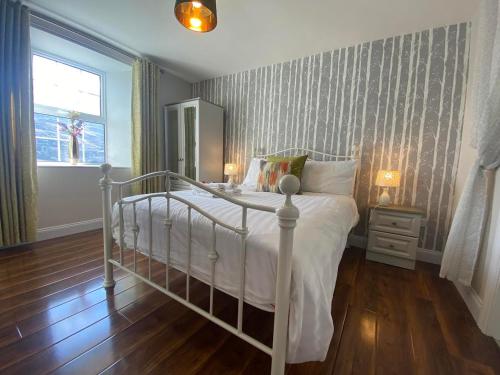 a bedroom with a white bed and a mirror at Ceim house, Restful rural home Gap of dunloe, Killarney in Derrylea