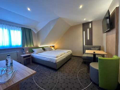 Habitación de hotel con cama, escritorio y TV. en Rothsee Hotel, en Allersberg