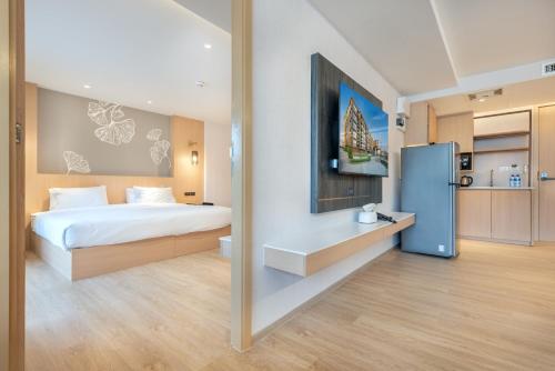 a bedroom with a bed and a refrigerator in it at Salaya One Hotel & Service Apartment in Salaya