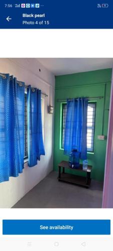 a picture of a room with blue curtains and a window at Black pearl in Alleppey