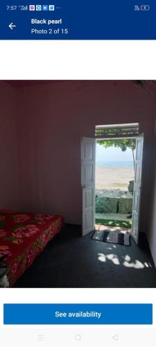 an open door to a room with a bed and a window at Black pearl in Alleppey