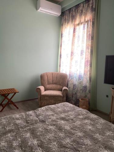 a bedroom with a bed and a chair and a television at Comfortable Apartment Balakhvani in Kutaisi