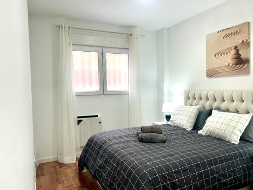 1 dormitorio con 1 cama con manta azul y ventana en Bustos Dreams, en Madrid
