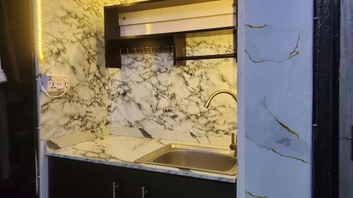 uma casa de banho com um lavatório e uma parede em mármore em Weltons Apartments em Ikeja