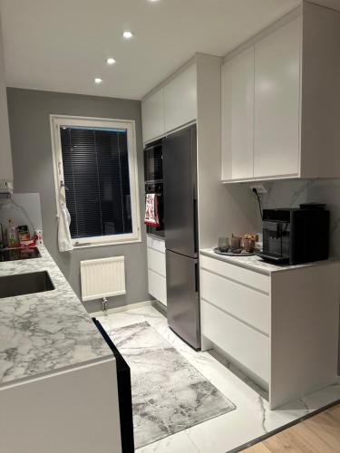 uma cozinha com armários brancos e um frigorífico preto em Välkomsthörnet em Estocolmo