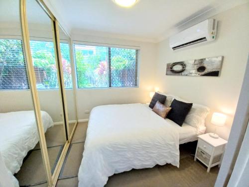 1 Schlafzimmer mit 2 Betten und einem Fenster in der Unterkunft Palm Garden Villa-Apt - Tropical Oasis at Cronulla Beach in Cronulla