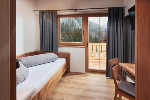 a bedroom with a bed and a desk and a window at Panoramahotel Burgeck in Krimml