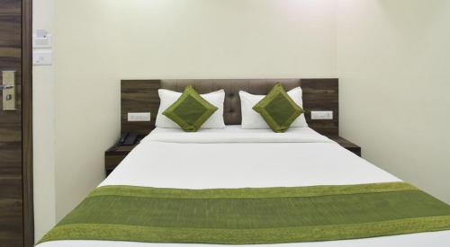 a bedroom with a white bed with green pillows at Hotel Palliate in Ahmedabad