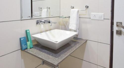 La salle de bains est pourvue d'un lavabo blanc sur un comptoir. dans l'établissement Hotel Palliate, à Ahmedabad