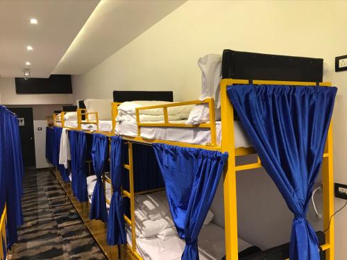 a room with three bunk beds with blue curtains at New Mango Dormitory in Mumbai