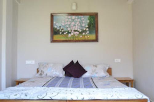 a bedroom with a bed with a picture on the wall at The Gingko Eyrie , Kalimpong in Kalimpong