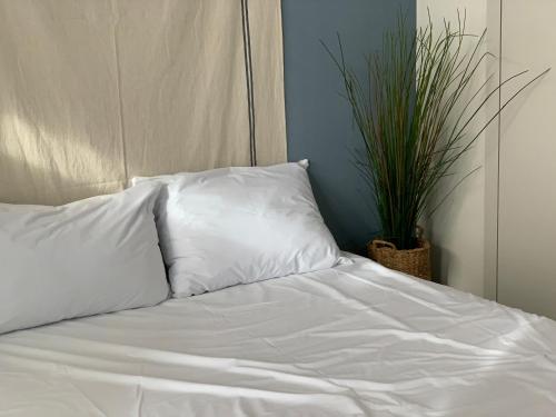 a white bed with two pillows and a plant at Landmark Stay in Songdo in Incheon