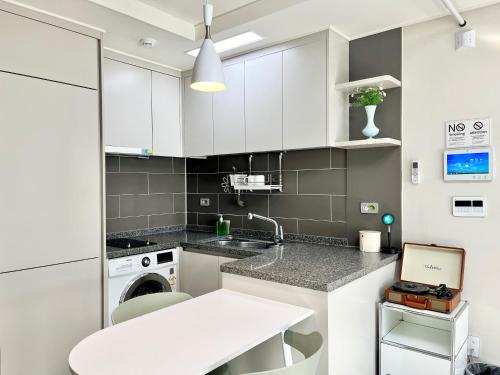 a kitchen with white cabinets and a washing machine at Landmark Songdo Stay in Incheon