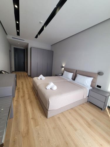 a bedroom with a large white bed and wooden floors at Toer Hotel & SPA in Sarandë
