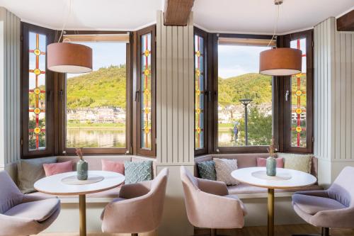 a room with two tables and chairs and windows at Hotel Weinhof in Cochem