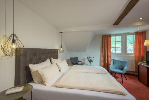 - une chambre avec un grand lit et une chaise bleue dans l'établissement Hotel Weinhof, à Cochem