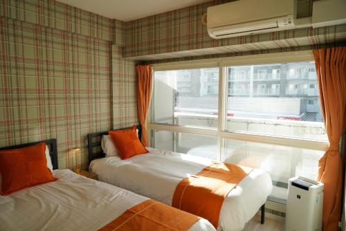 twee bedden in een kamer met een raam bij SAPPORO HILLS in Sapporo