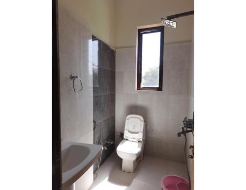 a bathroom with a toilet and a tub and a window at Hotel Ranthambhore Palace, Sawai Madhopur, RJ in Sawāi Mādhopur