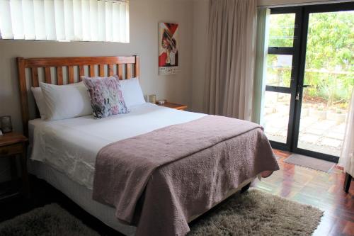 a bedroom with a bed and a large window at Traveller's Rest, Reebok in Mossel Bay