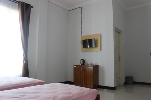 - une chambre avec 2 lits et une télévision murale dans l'établissement Lutjanus Guest House, à Majangan