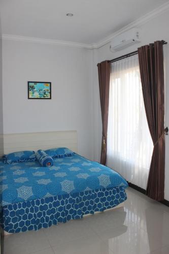 - une chambre avec un lit bleu et une fenêtre dans l'établissement Lutjanus Guest House, à Majangan