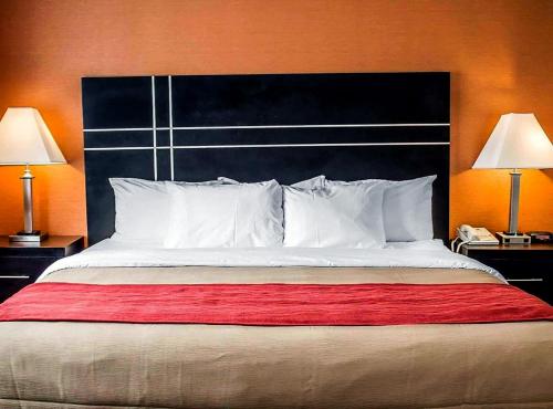 a large bed with a black headboard and two lamps at Norwood Inn Statefair Grounds in Columbus