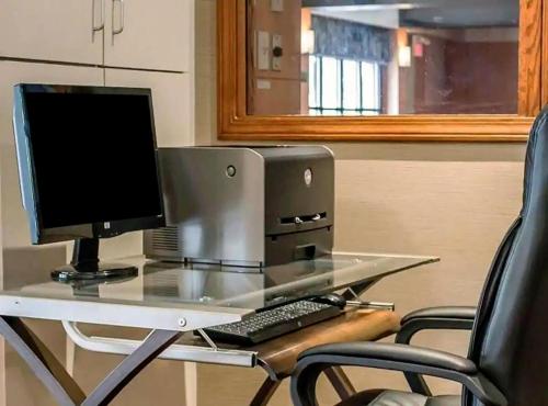 a computer on a glass desk with two chairs at Norwood Inn Statefair Grounds in Columbus
