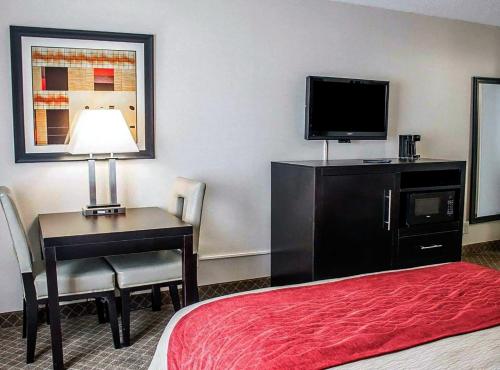 a hotel room with a bed and a desk with a television at Norwood Inn Statefair Grounds in Columbus