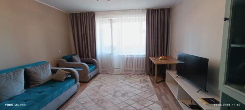 ein Wohnzimmer mit einem blauen Sofa und einem TV in der Unterkunft Lux Home на берегу Ульбы in Öskemen