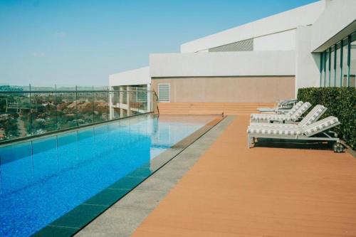 a swimming pool with lounge chairs next to a building at Menlyn Maine Trilogy Apartment 1518 in Pretoria