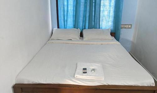 - un lit avec une couverture blanche et un téléphone portable dans l'établissement FabExpress Aabriz Residency, à Ernakulam