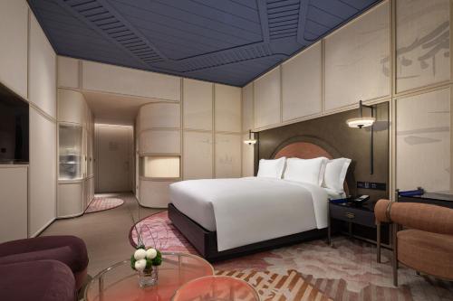 a bedroom with a large bed and a living room at Hotel Indigo Wuxi Taihu New City in Wuxi